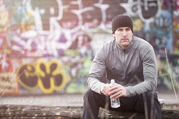 USA, Washington, Seattle, man in workout wear in front of graffiti wall. Photo: Take A Pix Media