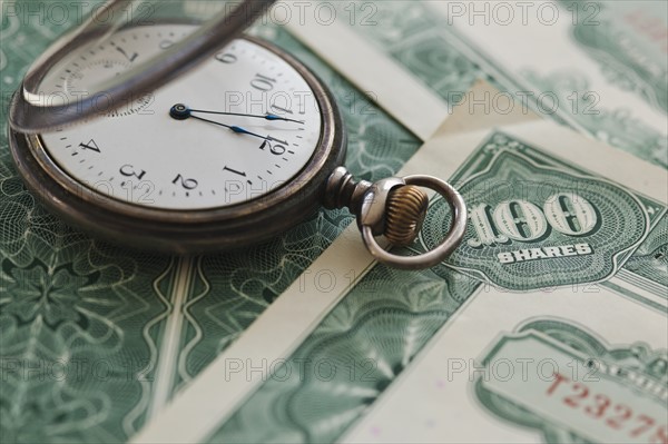 Close up of pocket watch and shares.