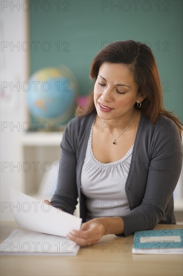 Female teacher sitting at desk in classroom.