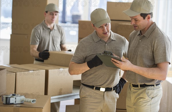 Men checking checklist in warehouse.