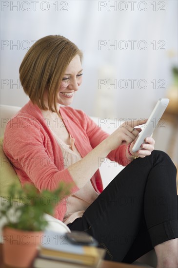 Woman sitting on sofa and using digital tablet.