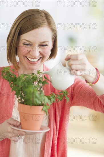 Woman watering potted plant.
