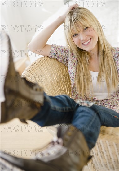 Young woman sitting in wicker chair. Photo : Jamie Grill Photography