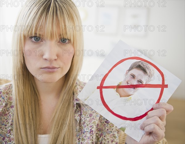 Young woman holding photograph of ex-boyfriend. Photo : Jamie Grill Photography