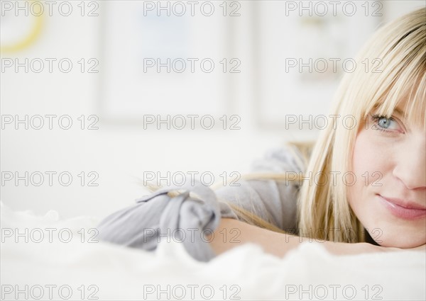 Young woman relaxing in bed. Photo : Jamie Grill Photography