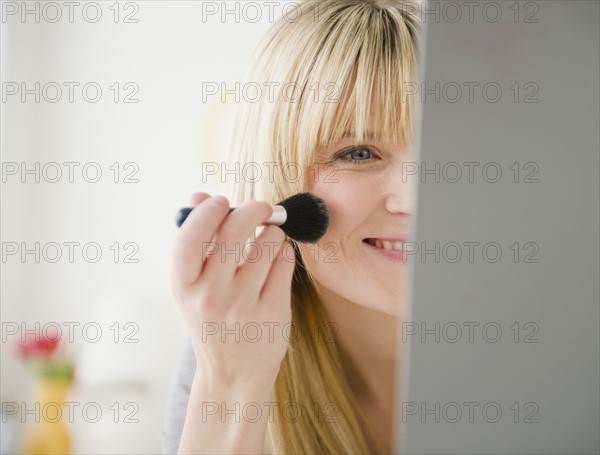 Young woman applying blush. Photo: Jamie Grill Photography