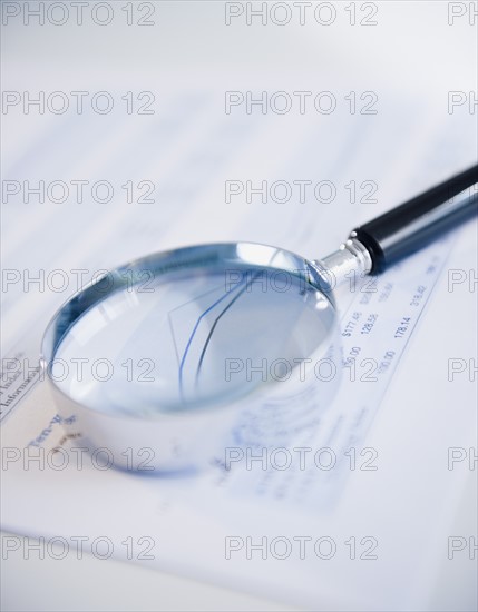 Studio shot of magnifying glass on document. Photo : Jamie Grill Photography