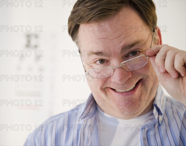 Portrait of man lowering glasses. Photo: Jamie Grill Photography