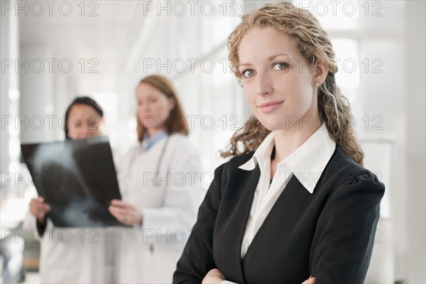 Portrait of businesswoman with doctors in background. Photo: Mark Edward Atkinson