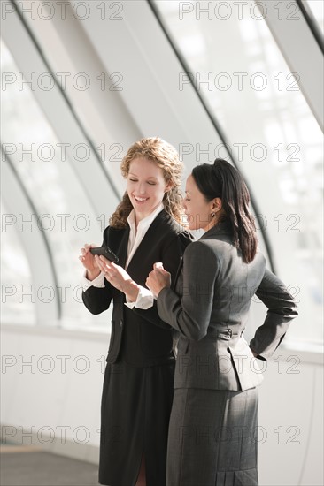Businesswomen looking at cell phone. Photo: Mark Edward Atkinson