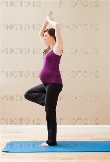 Young pregnant woman exercising, standing on one leg. Photo: Mike Kemp