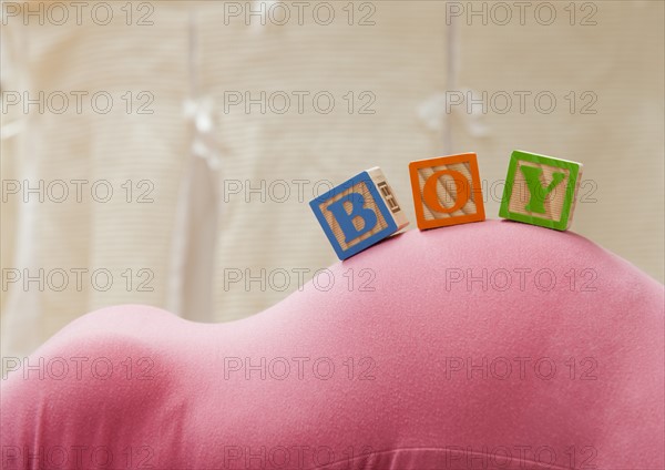 Wooden blocks with letters on pregnant woman's belly, reading as boy. Photo: Mike Kemp