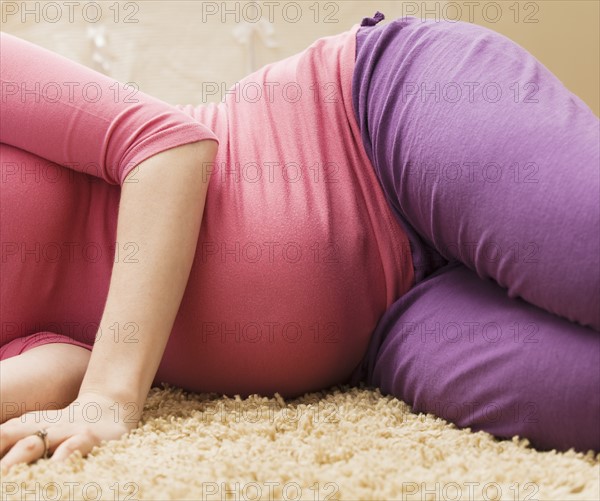 Pregnant woman laying on rug. Photo : Mike Kemp
