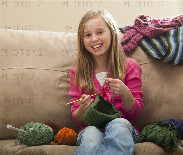 Cheerful girl (8-9) knitting woolly hat. Photo: Mike Kemp