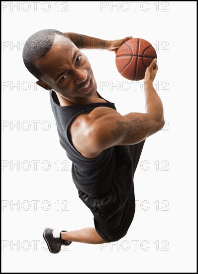 Studio shot of young man playing basketball. Photo : Mike Kemp