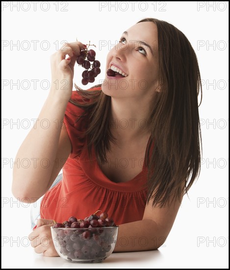 Young woman eating grapes. Photo : Mike Kemp