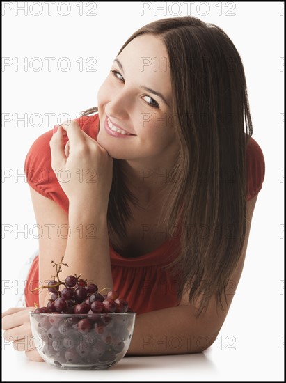 Studio portrait of young woman with grapes. Photo: Mike Kemp