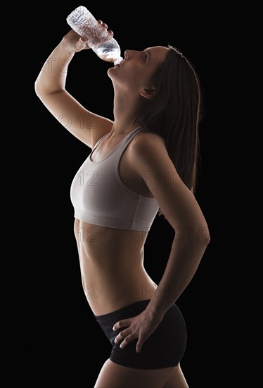 Young woman drinking water from bottle. Photo : Mike Kemp