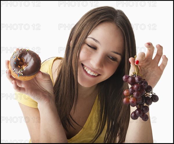 Young woman holding grapes and doughnut. Photo : Mike Kemp