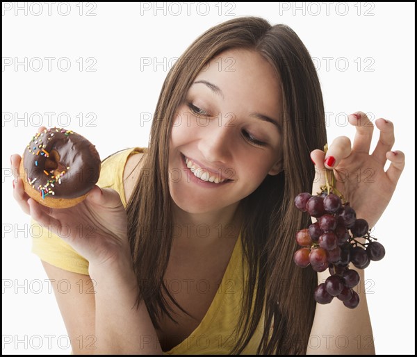 Young woman holding grapes and doughnut. Photo: Mike Kemp