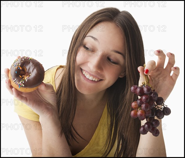 Young woman holding grapes and doughnut. Photo : Mike Kemp