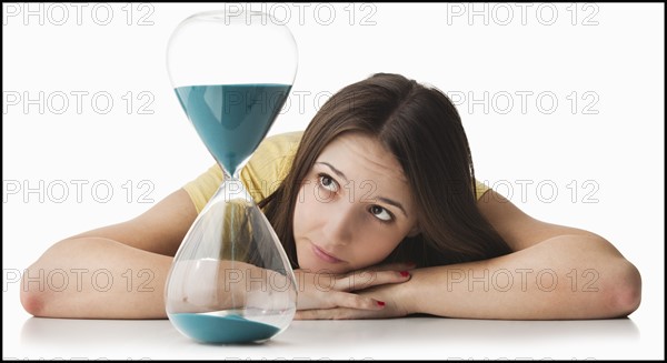 Young woman watching hourglass. Photo : Mike Kemp