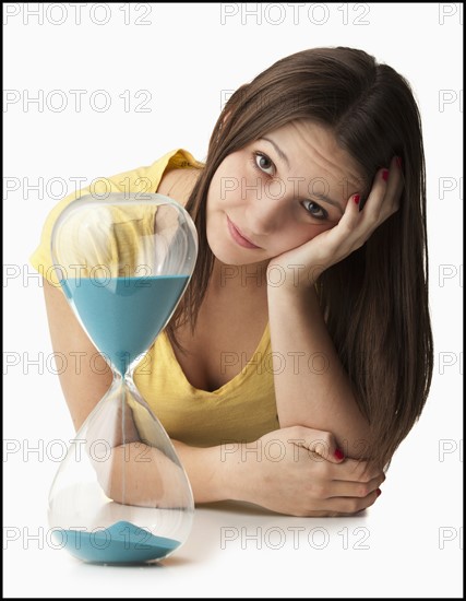 Studio portrait of young woman with hourglass. Photo: Mike Kemp