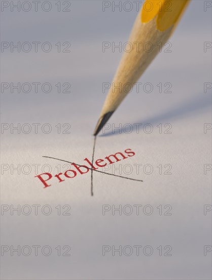 Studio shot of pencil crossing out the word problems from piece of paper. Photo : Daniel Grill