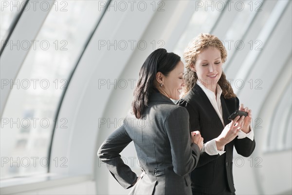 Businesswomen looking at cell phone. Photo : Mark Edward Atkinson