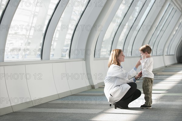 Female doctor talking to boy (6-7) in corridor. Photo : Mark Edward Atkinson