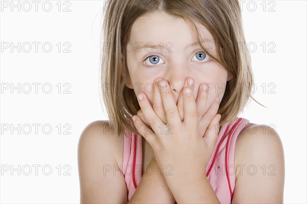 Studio portrait of girl (6-7) covering mouth. Photo: Justin Paget