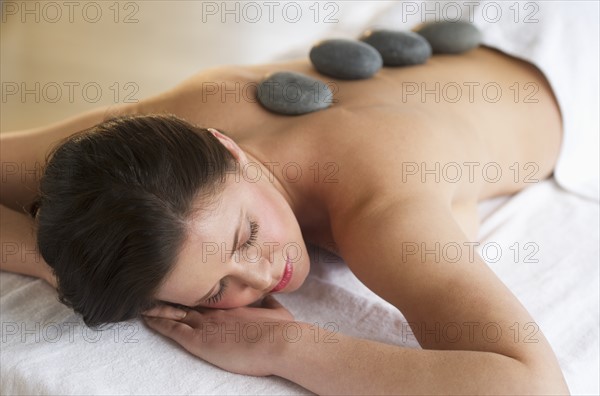 Woman receiving hot stone therapy.