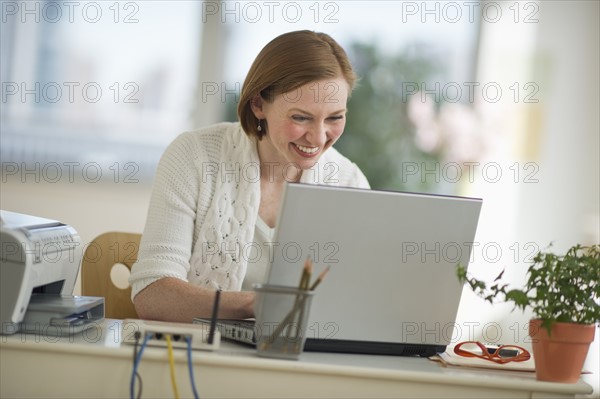 Woman working on laptop at home office.