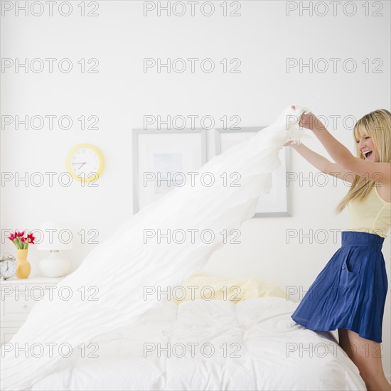 Young woman making bed. Photo : Jamie Grill Photography