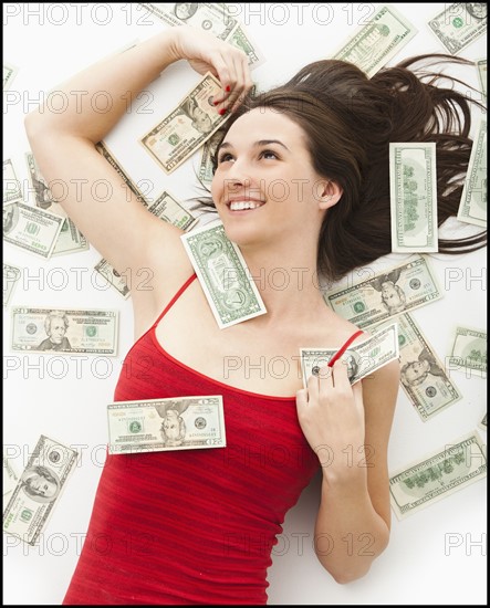 Young woman lying in money. Photo : Mike Kemp