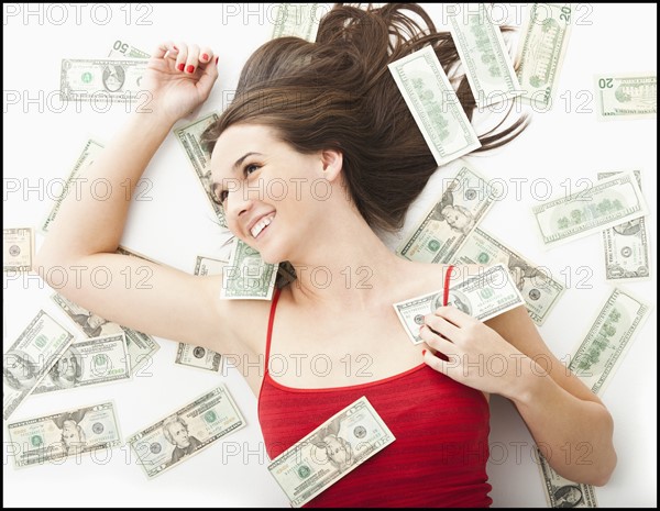 Young woman lying in money. Photo: Mike Kemp