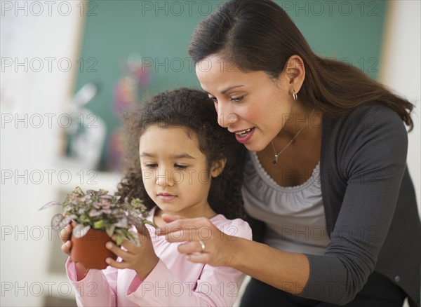 Girl (6-7) holding potted plant with female teacher.