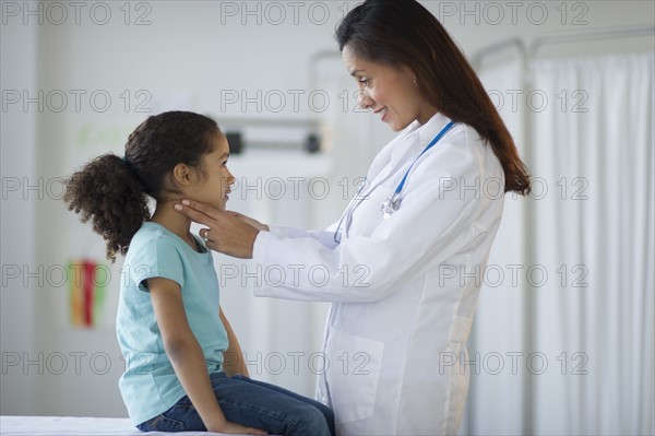 Female pediatrician examining girl (6-7) in doctor's office.