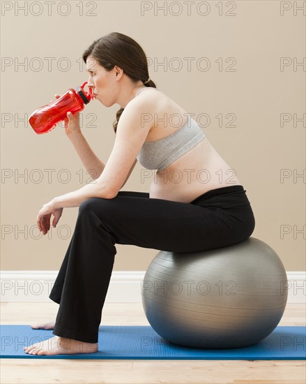 Young pregnant woman taking break from exercise. Photo : Mike Kemp