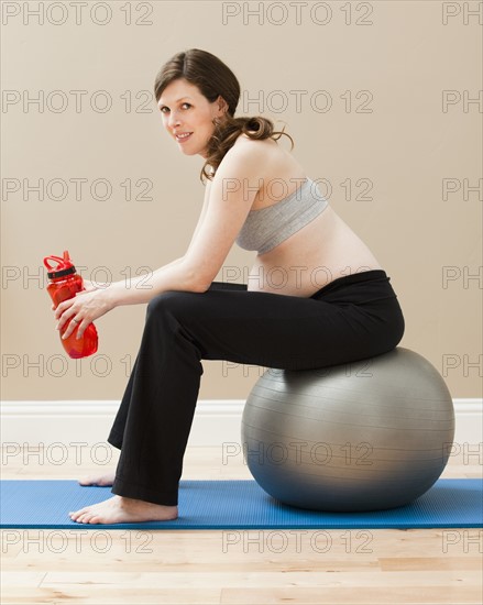 Young pregnant woman taking break from exercise. Photo : Mike Kemp