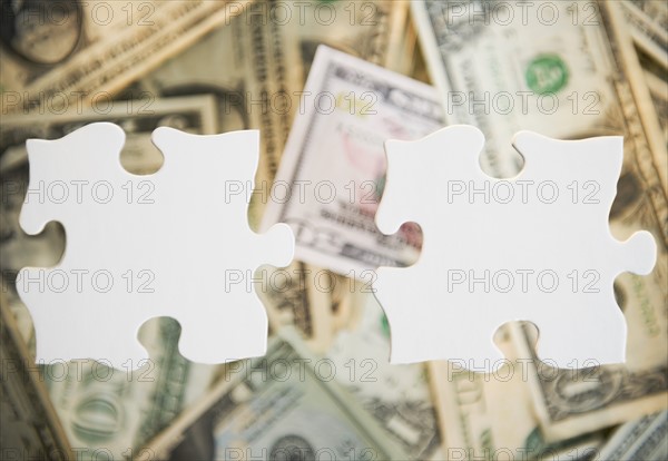 Studio shot of jigsaw pieces against heap of money. Photo : Jamie Grill Photography