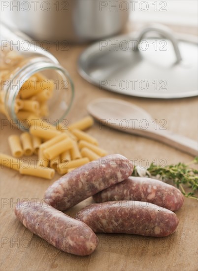 Raw sausage and pasta on kitchen table.