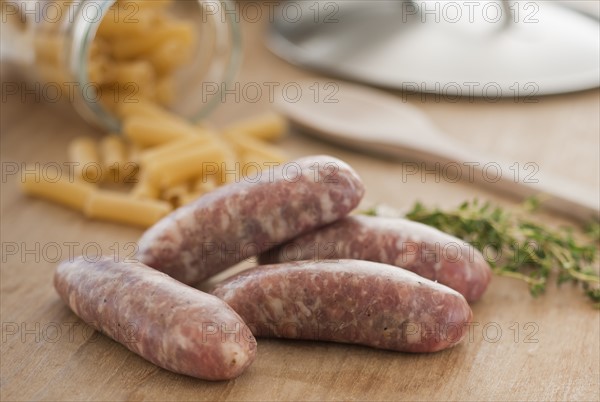 Raw sausage and pasta on kitchen table.