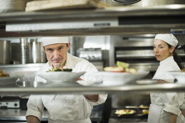 Chefs preparing food in kitchen.