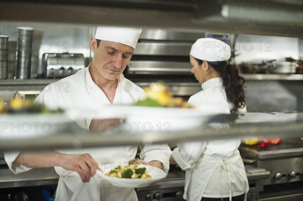 Chefs preparing food in kitchen.