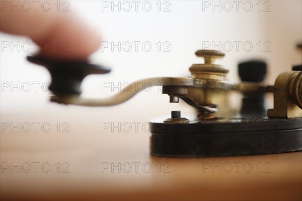 Finger pressing telegraph key, studio shot.