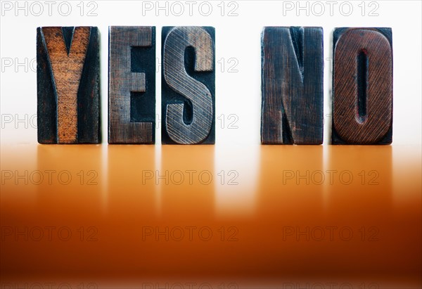Wooden letter blocks spelling 'yes' and 'no', studio shot.