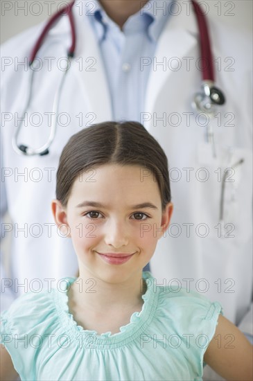 Portrait of girl (8-9), with doctor behind.