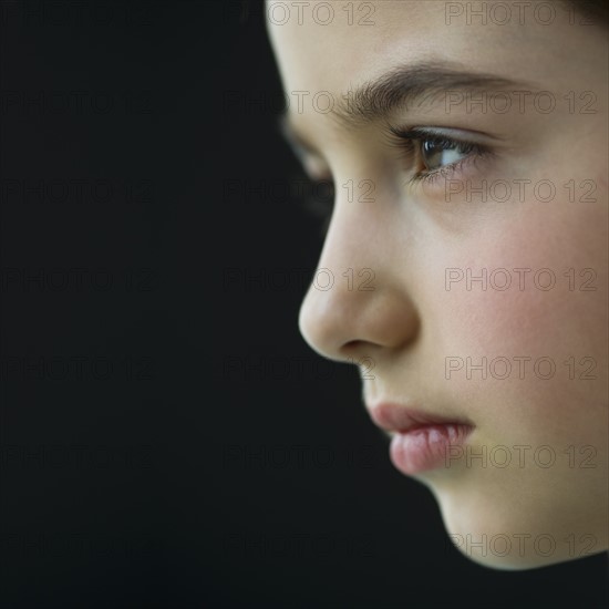 Studio profile of girl (8-9) on black background.