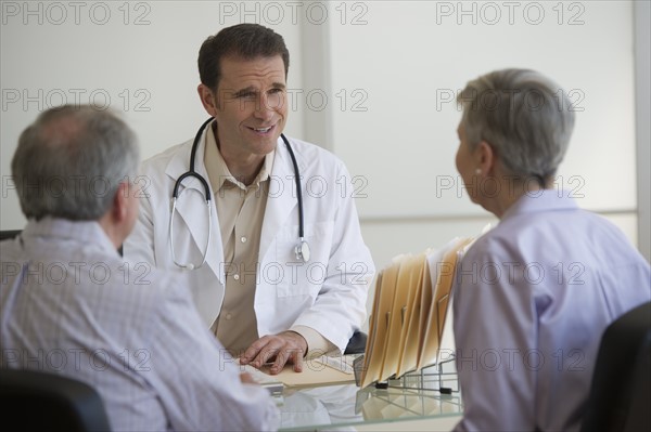 Doctor and senior couple talking in office.